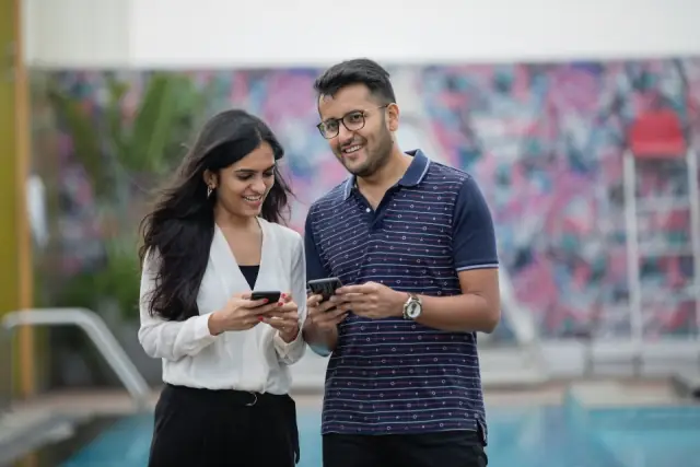 Une femme et un homme consultent leur téléphone en souriant