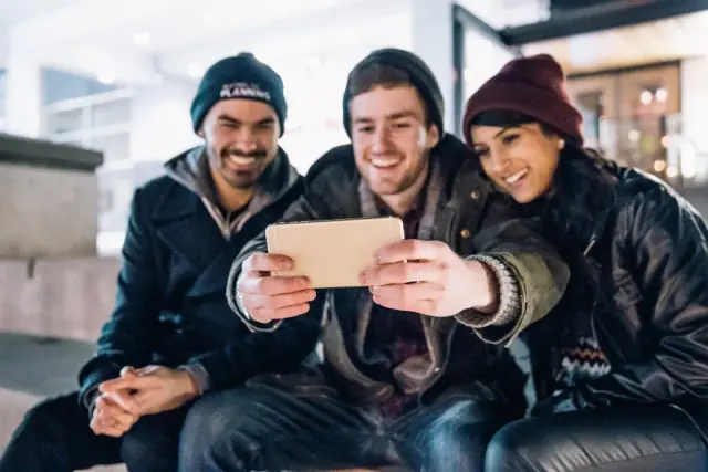 Quatre jeunes regardent ensemble un téléphone