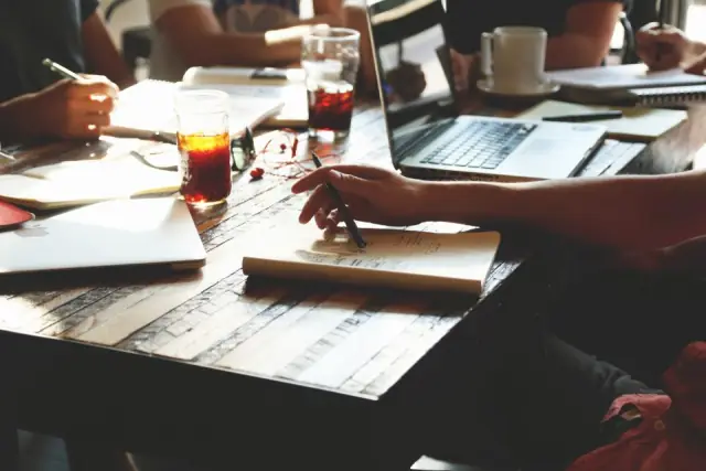 Mains de plusieurs personnes travaillant ensemble sur des documents et un ordinateur